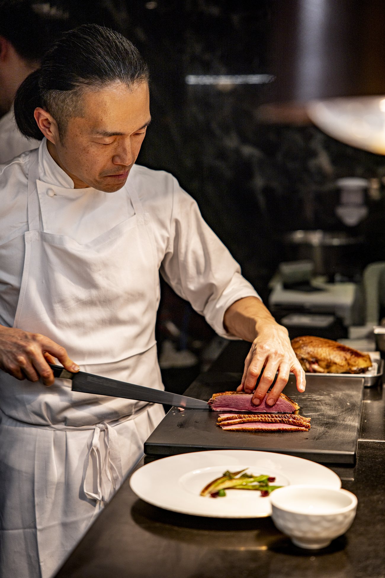 Le chef Yoshitaka Takayanagi dresse une assiette au passe de la cuisine de Granite